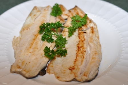 Rainbow trout cooked and topped with parsley on a plate