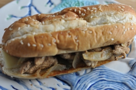 Chicken cheesesteak with chicken, onions, bell peppers on a toasted hoagie bun for the perfect philly cheesesteak on a blue and white plate.