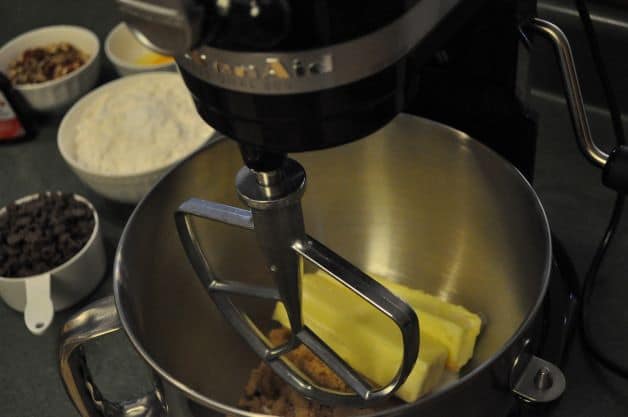 Stand mixer with butter and sugar. Other ingredients for best chocolate chip cookies in background.