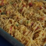 Chicken spaghetti made with rotel diced tomatoes and green chilies smothered in Velveeta cheddar cheese in a casserole dish