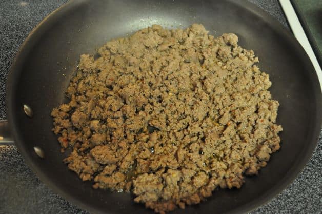 Ground sausage browning in a skillet.