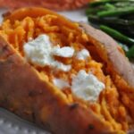 Whole sweet potato cooked in instant pot topped with butter and ready to eat on a plate.