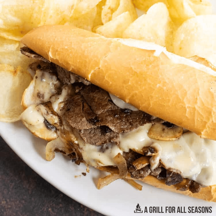 Blackstone Philly Cheesesteak Griddle Steak Sandwich with melted cheese and onions on a hoagie bun.