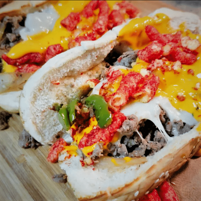 Philly cheesesteak sandwiches prepared on a griddle.