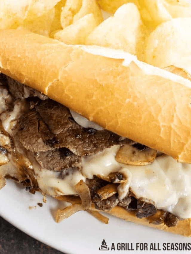 Blackstone Philly Cheesesteak Griddle Steak Sandwich with melted cheese and onions on a hoagie bun.