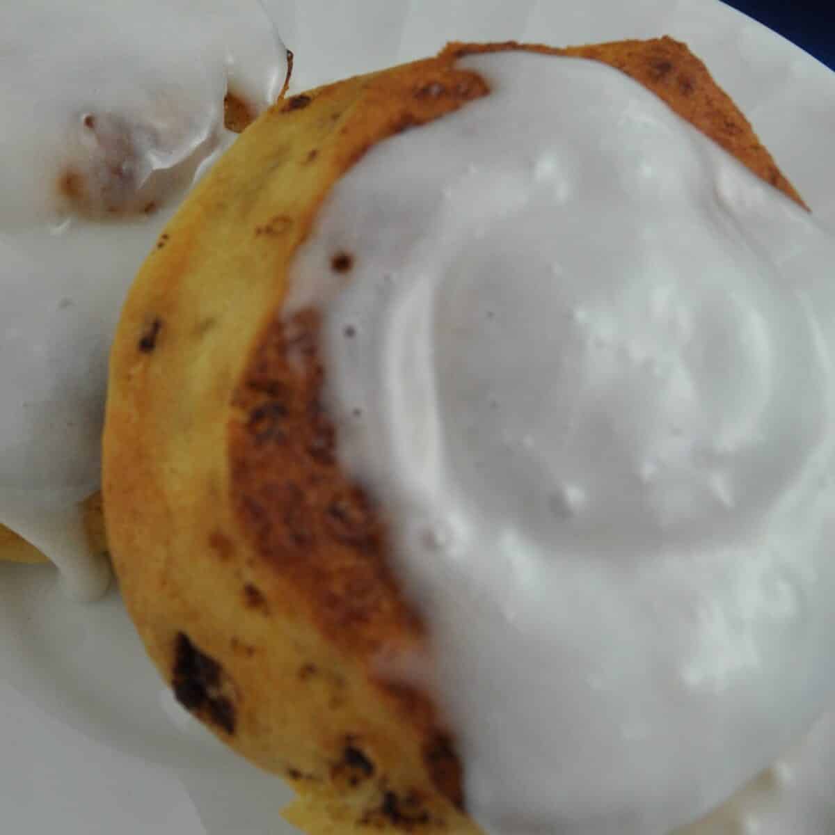 Cinnamon rolls in air fryer with sweet icing running down the side.