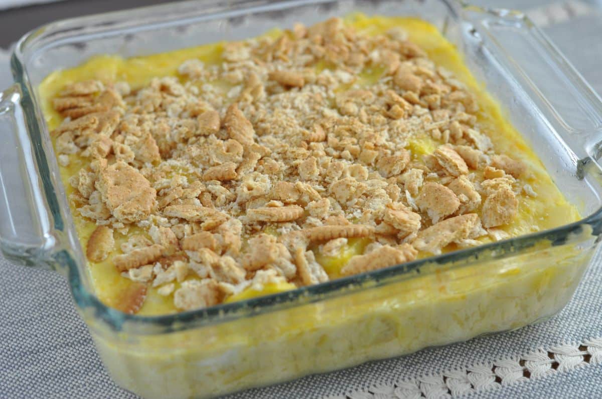 Easy squash casserole recipe ready to bake with yellow squash in a casserole dish covered with Ritz crackers.