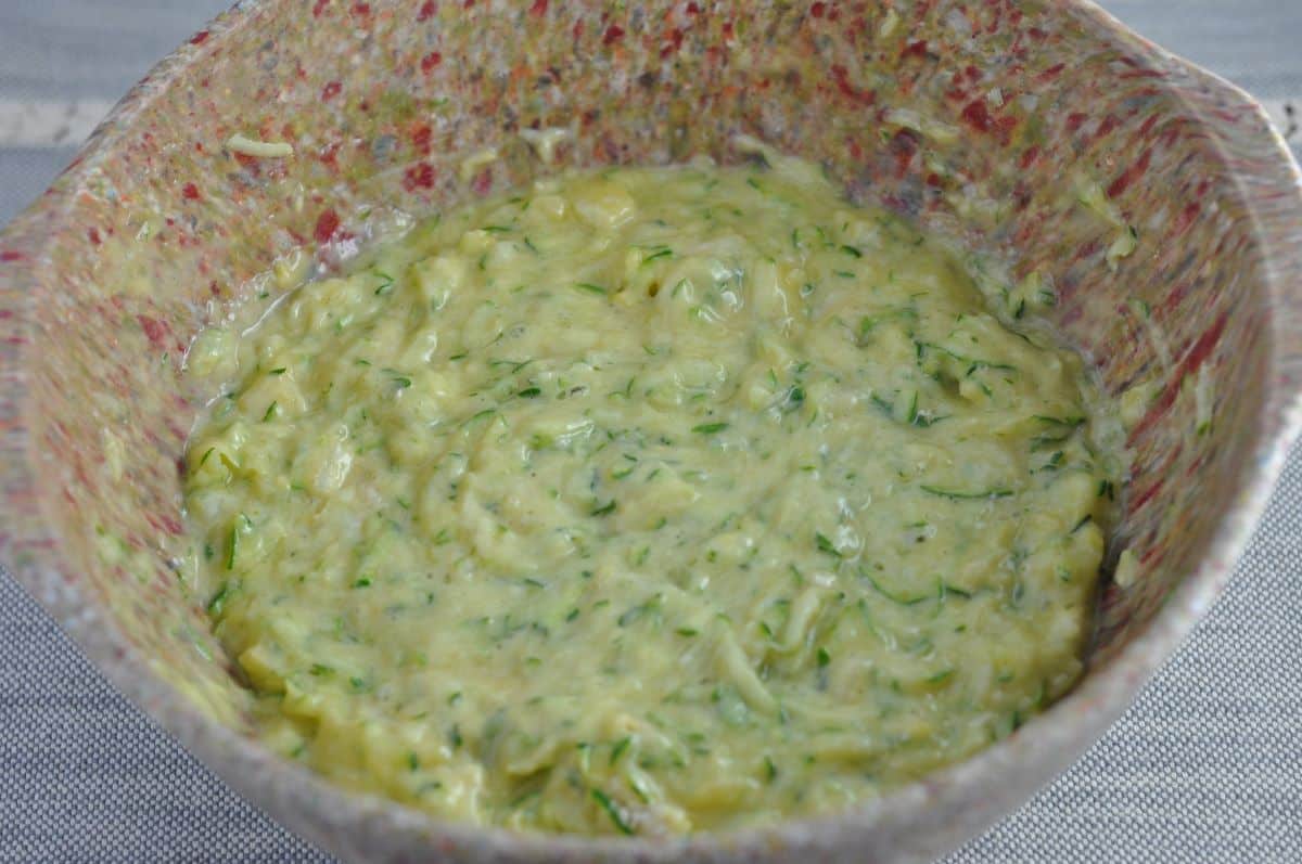 Zucchini souffle casserole ingredients in a bowl stirred.