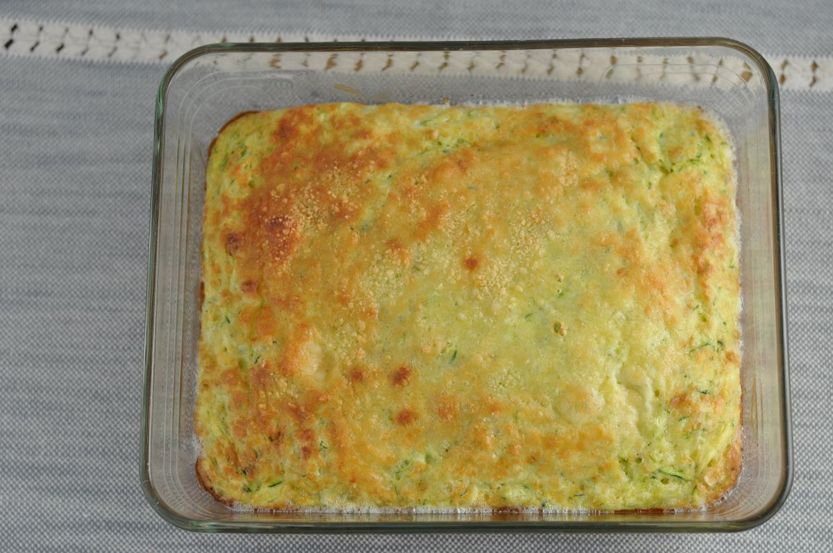 Zucchini souffle baked in a casserole dish topped with parmesan cheese and cooked until golden brown.