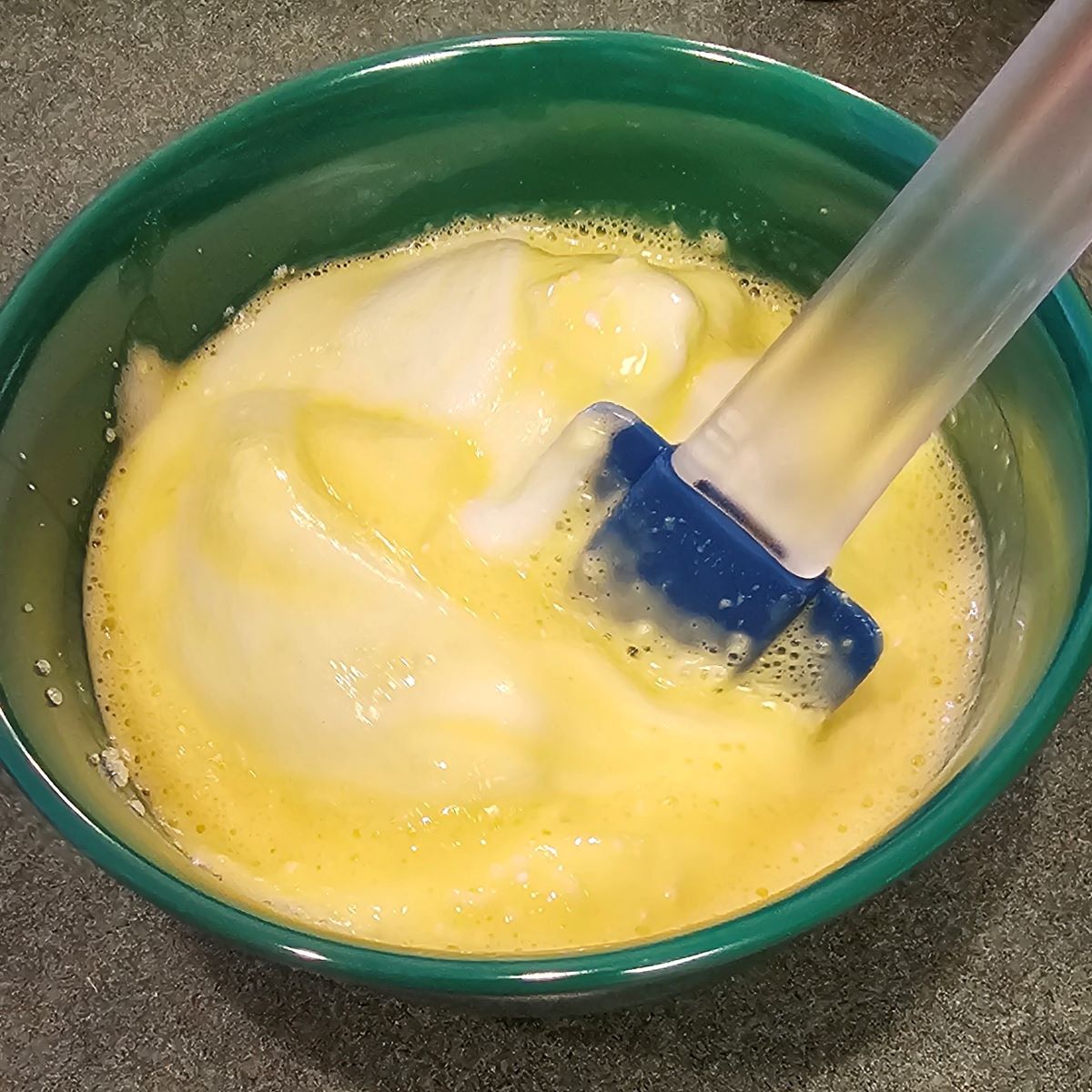 Recipe step of folding stiff egg whites into liquids and all-purpose flour mixture.