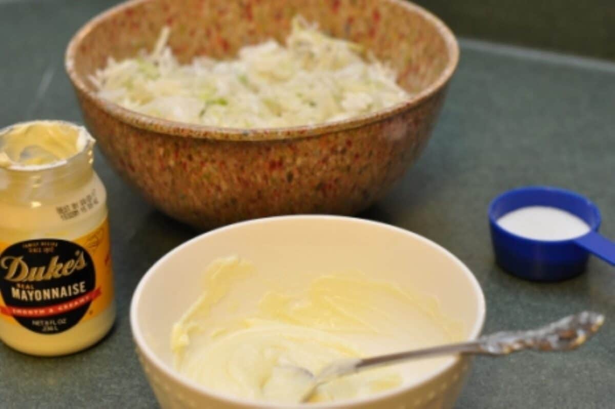 Homemade coleslaw dressing ingredients and being mixed in a bowl.
