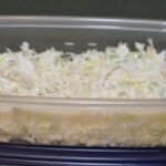 Easy coleslaw recipe in a plastic storage bowl prepared and ready to eat.