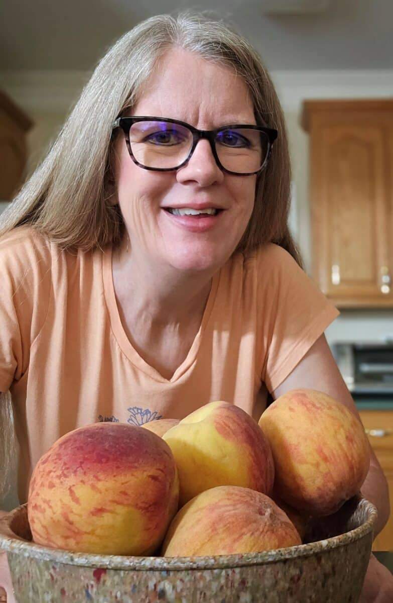 Picture of author of food and life path in front of bowl of peaches.