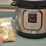 Fresh purple hull peas in a bag from the farmer's market next to an instant pot / pressure cooker on the kitchen cabinet.